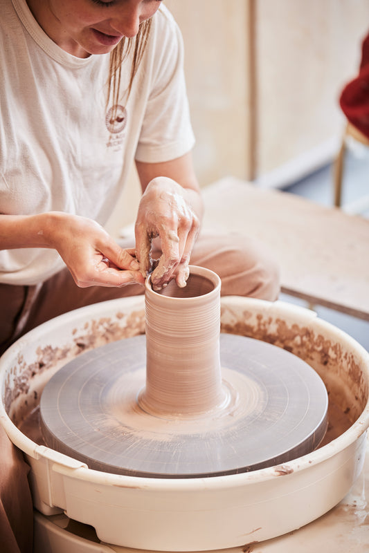 Personne qui tourne une forme cylindrique sur le tour de potier