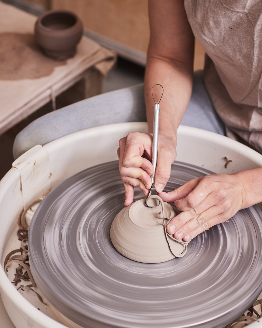 Main avec un outil qui tournasse une pièce de poterie sur un tour