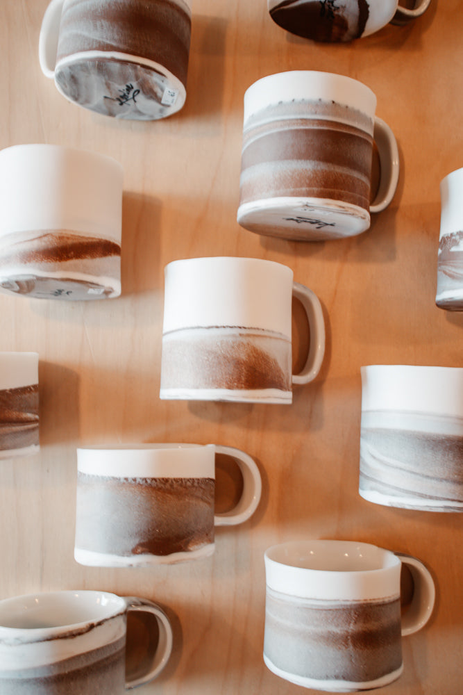 Des tasses en porcelaine marbrée d'argile brune sont posées sur une table.