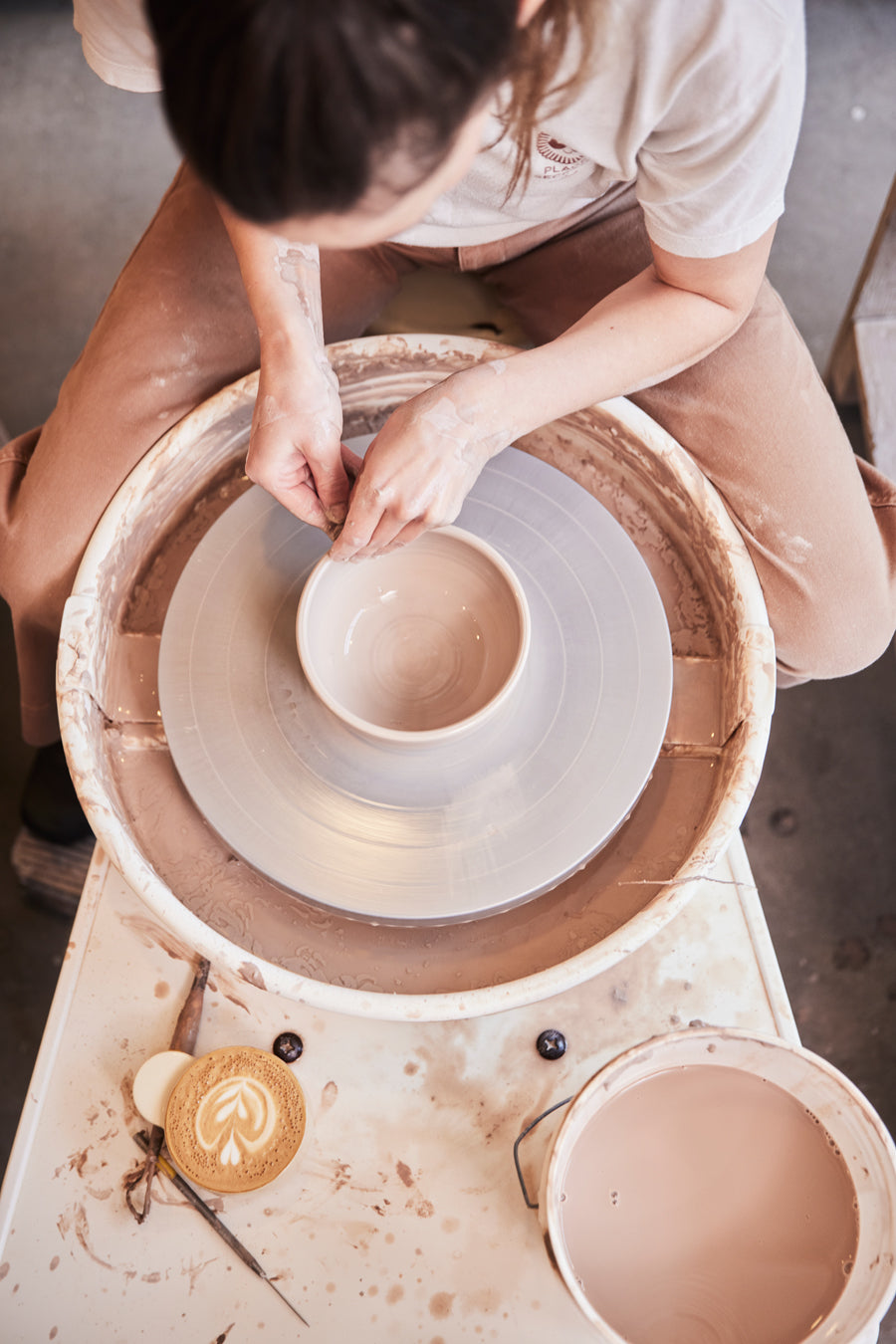 Vue de haut d'une personne qui fait de la poterie avec un café