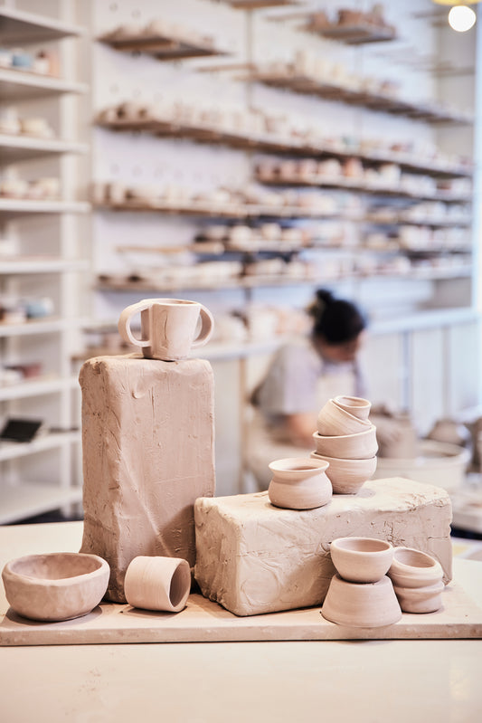 Bols et autres formes réalisées en argile avec des blocs de terre devant un studio de poterie