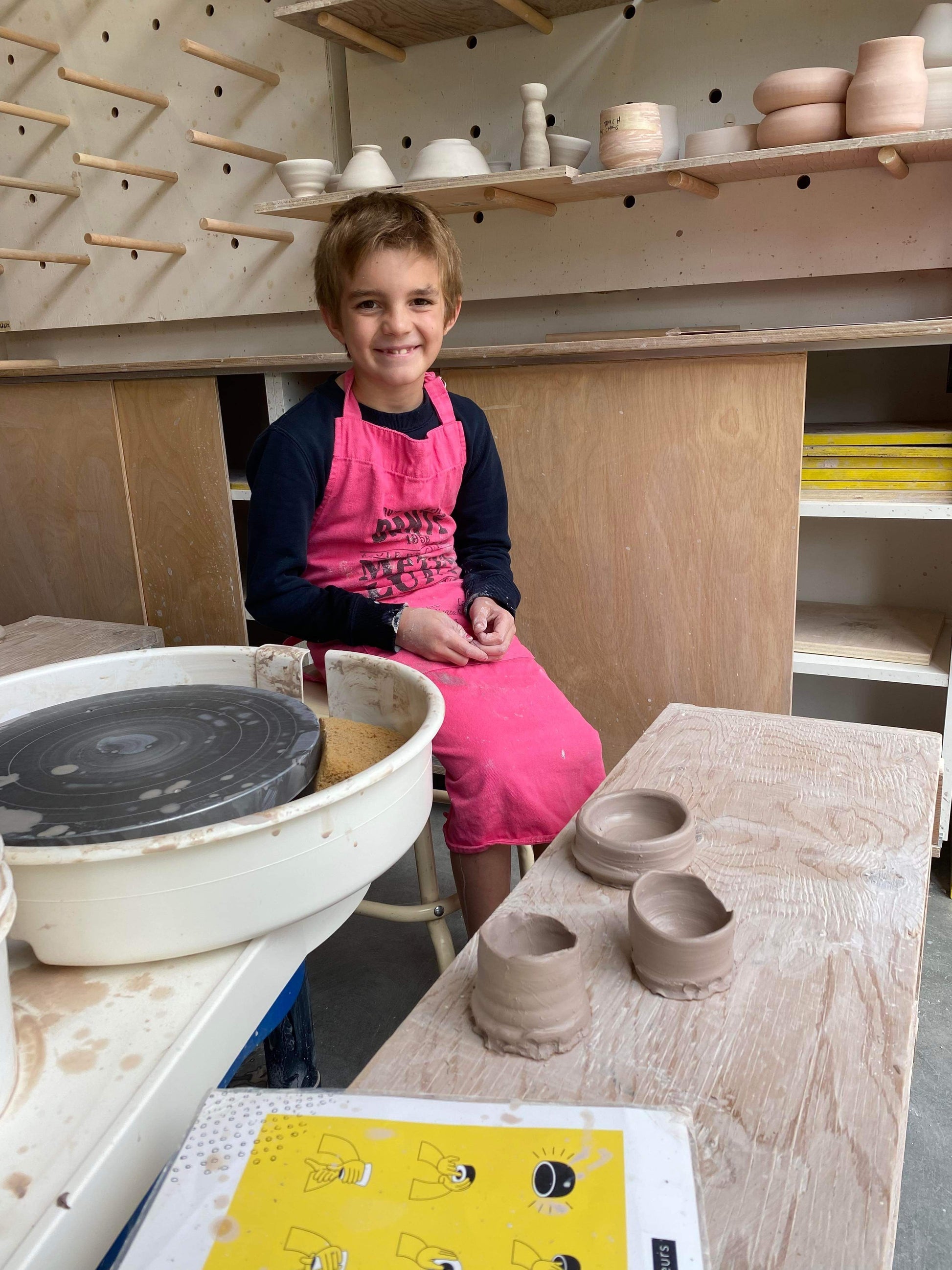 Enfant dans un atelier de poterie avec 3 petits bols